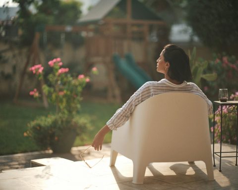 a woman sitting on a chair in a backyard