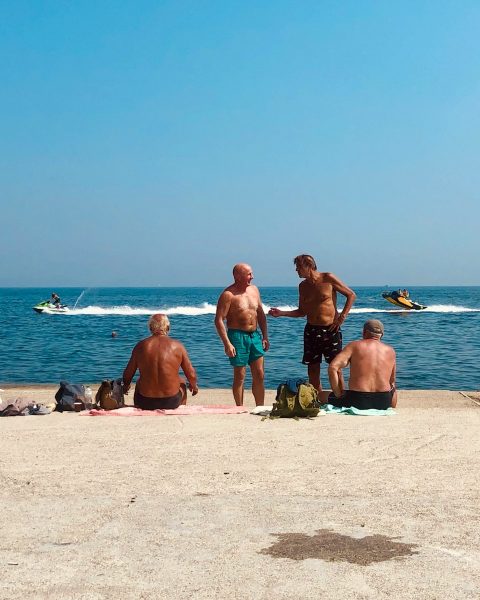 3 women and 2 men sitting on beach sand during daytime