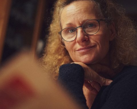 a woman wearing glasses looking at a mirror