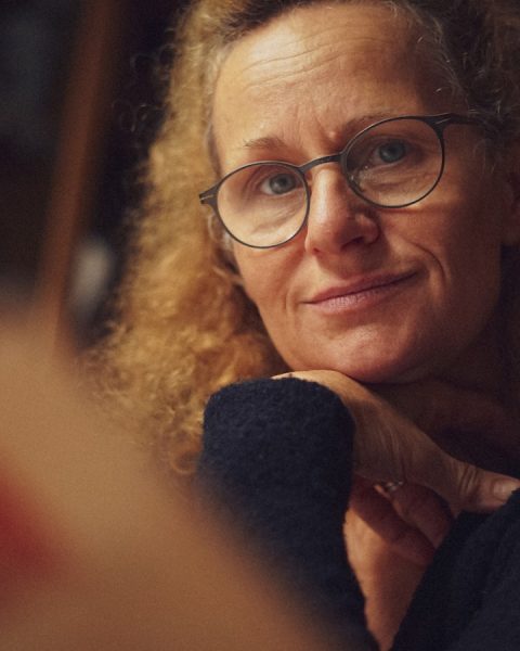 a woman wearing glasses looking at a mirror