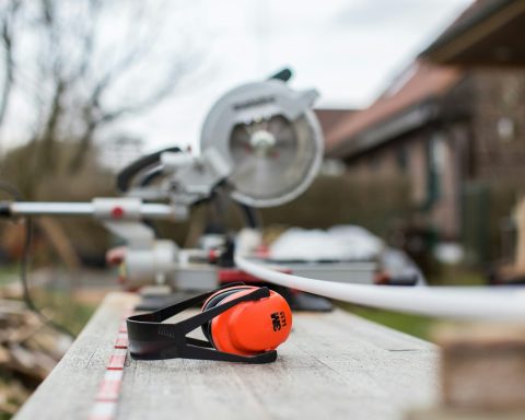 black and red 3M earmuffs beside miter saw