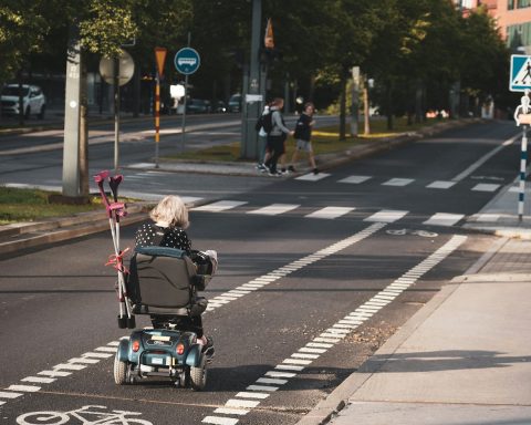 girl in black jacket riding on black and gray stroller on gray asphalt road during daytime