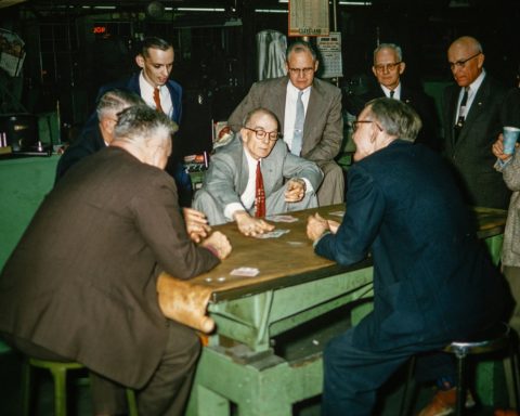 a group of men sitting around a table playing cards
