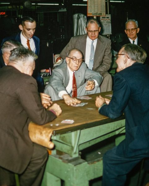 a group of men sitting around a table playing cards