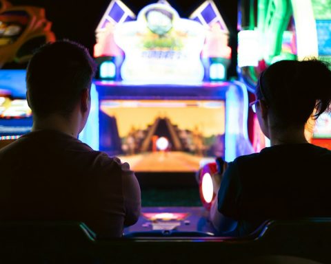 a couple of men sitting in a room with a large screen