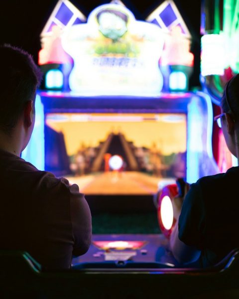 a couple of men sitting in a room with a large screen