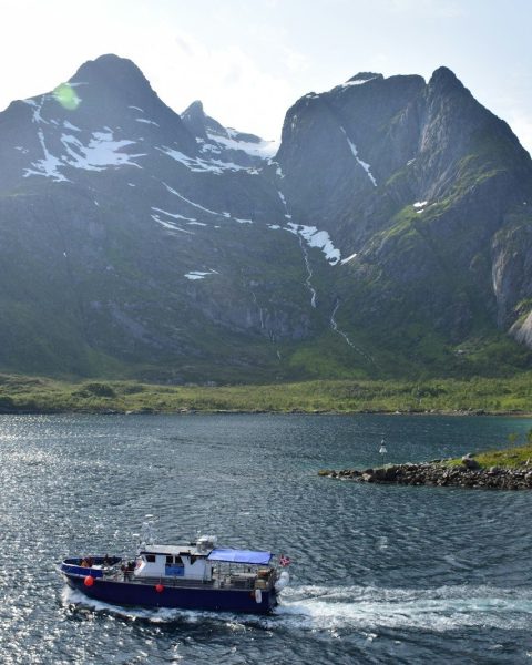 white and blue boat on water near mountain during daytime