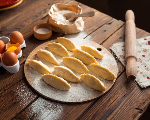 Oudere handen die een pan vasthouden in de keuken