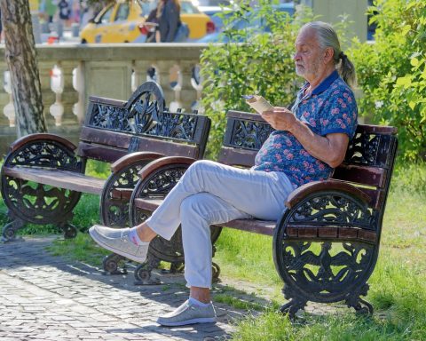 Een senior die genietend een non-fictie boek leest in de zomertuin