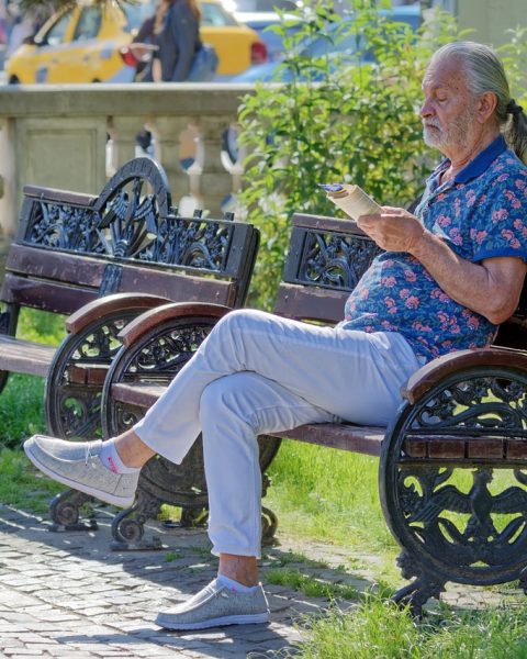 Een senior die genietend een non-fictie boek leest in de zomertuin
