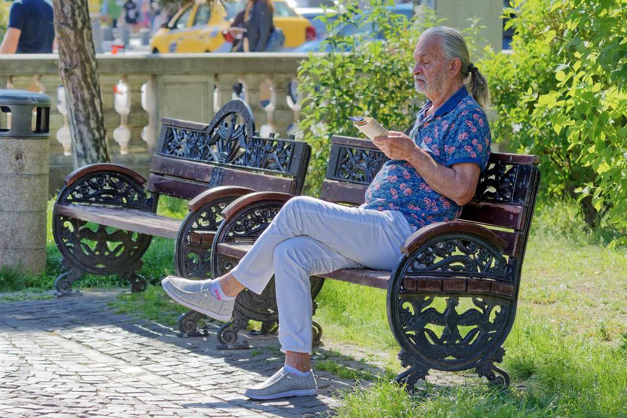 Een senior die genietend een non-fictie boek leest in de zomertuin