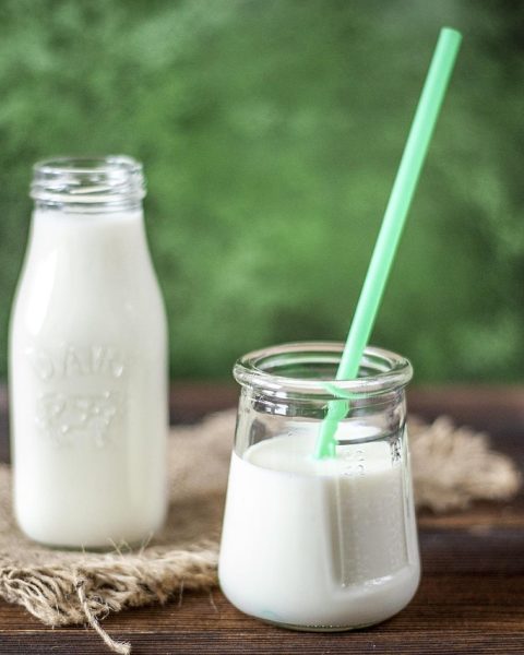 Een yoghurtdrankje met plantensterolen op een ontbijttafel naast een bord met boterhammen