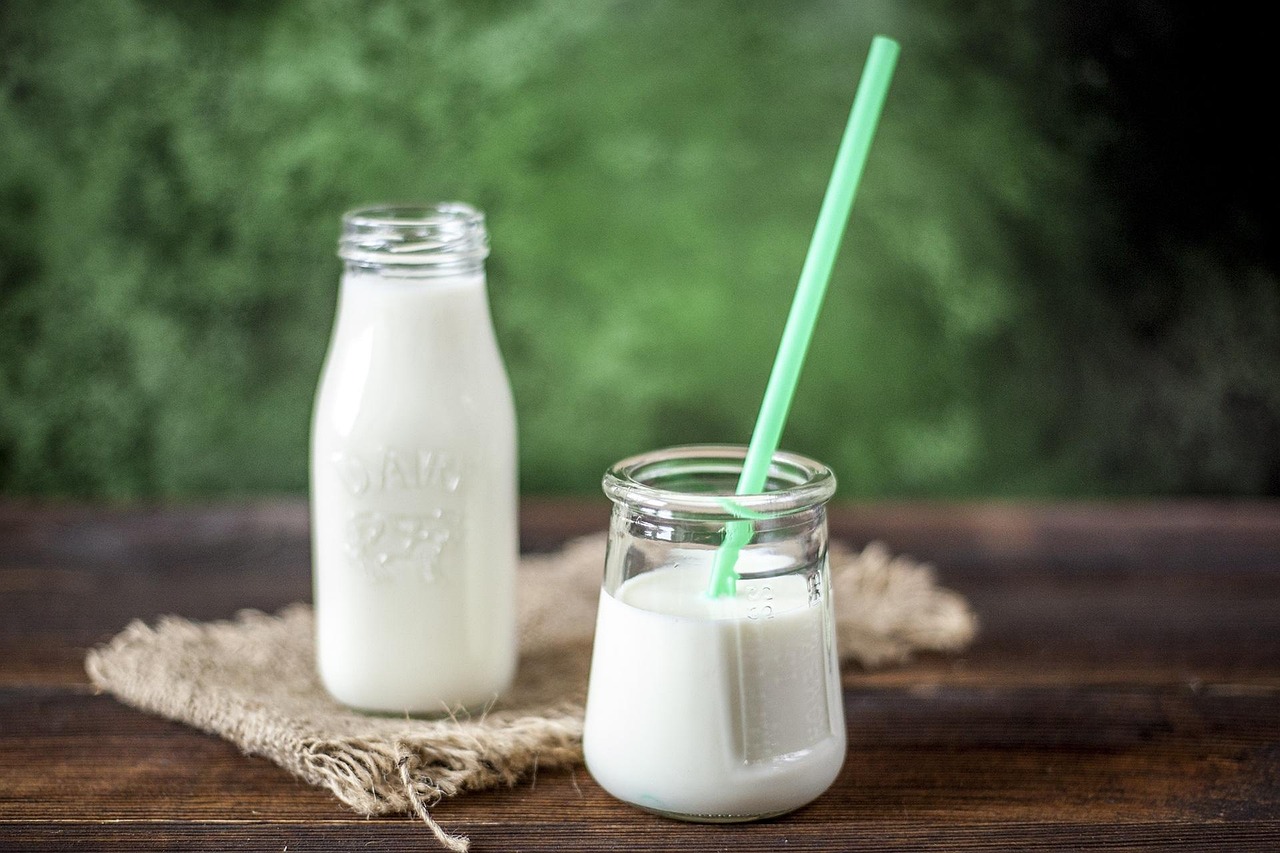 Een yoghurtdrankje met plantensterolen op een ontbijttafel naast een bord met boterhammen