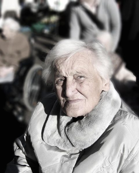 Een senior vrouw op groepsreis, lachend met medepassagiers tijdens een begeleid uitstapje