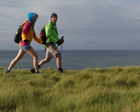 man and woman wearing backpacks on green grass field during daytime