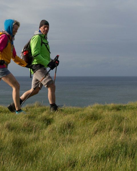 man and woman wearing backpacks on green grass field during daytime