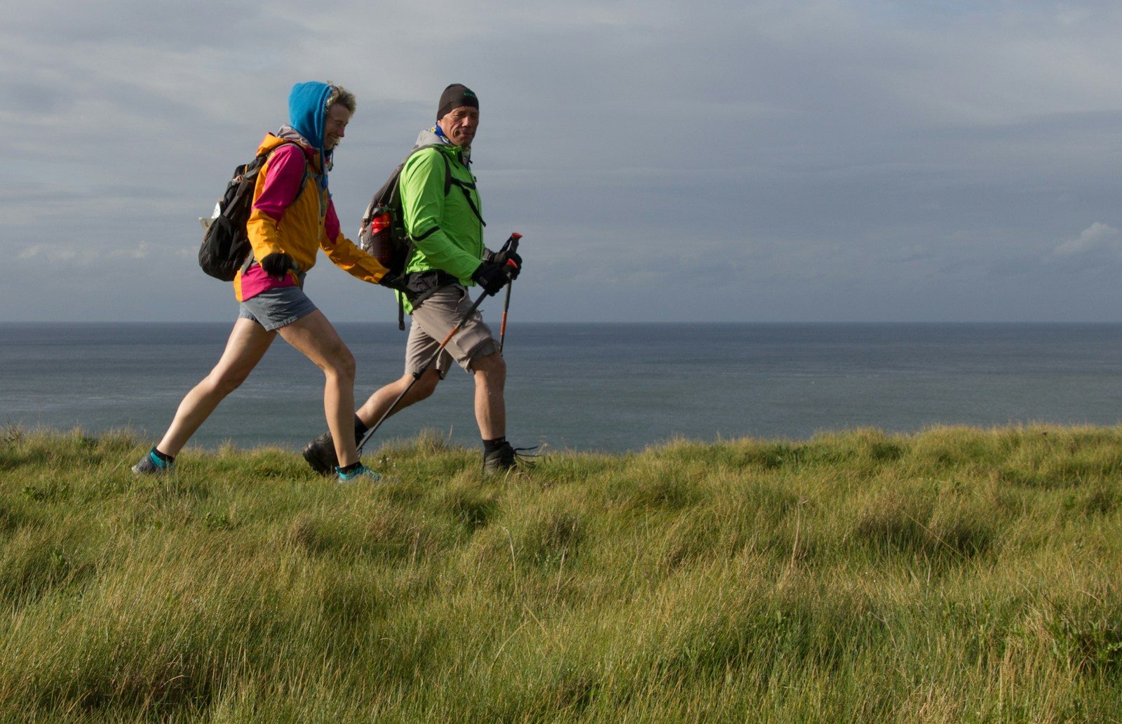 man and woman wearing backpacks on green grass field during daytime