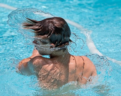 Een senior zwemt rustige baantjes in een buitenzwembad op een zonnige zomerdag