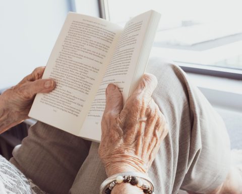 Een oudere vrouw leest een boek op een rustige plek in de buurt