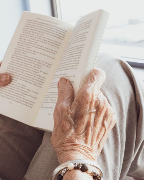 Een oudere vrouw leest een boek op een rustige plek in de buurt
