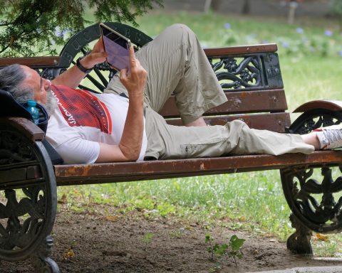 Senior die ontspannen buiten zit te lezen op een e-reader