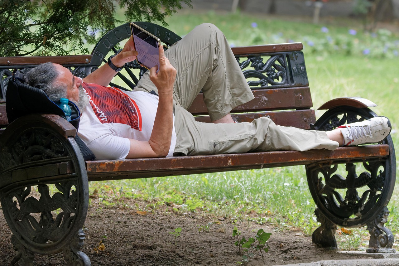 Senior die ontspannen buiten zit te lezen op een e-reader