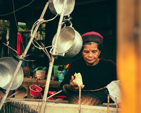 Oudere vrouw die maaltijden portionneert in bakjes in de keuken