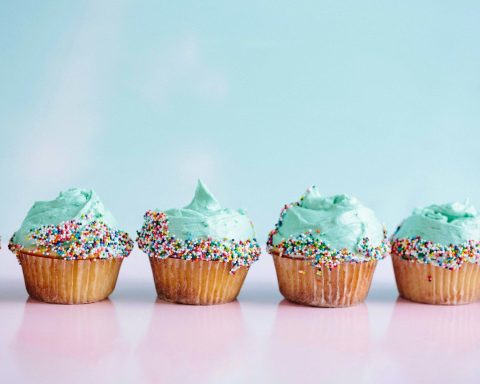 six teal icing cupcakes with sprinkles