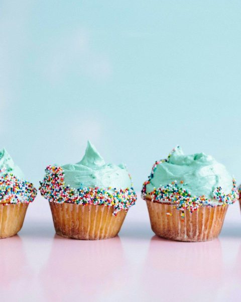 six teal icing cupcakes with sprinkles