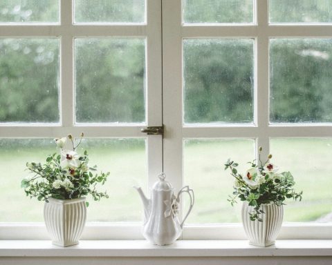 white teapot and tow flower vases on windowpane