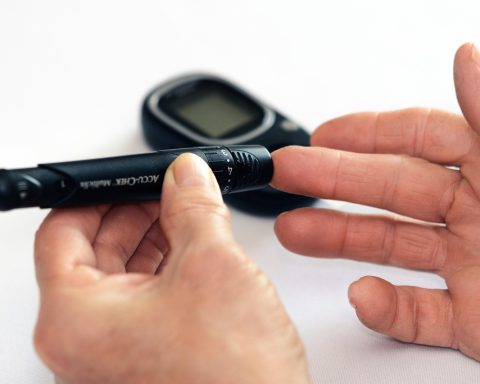 Een oudere vrouw meet haar bloeddruk thuis met een bovenarm-bloeddrukmeter