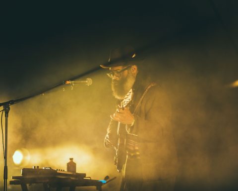 Een oudere man zingt met gevoel in een microfoon op een podium